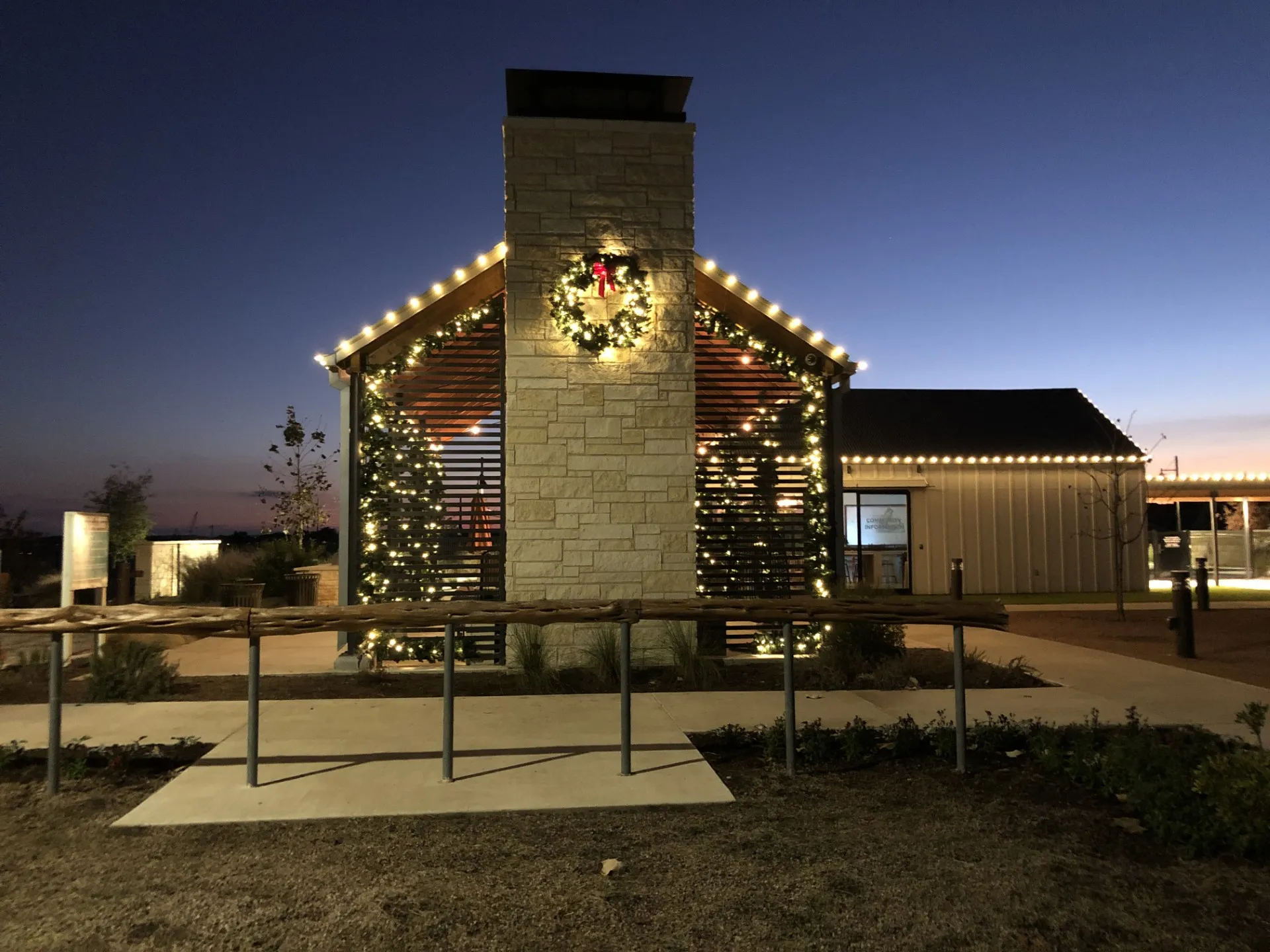 Community center framed with lit greenery and holiday lights