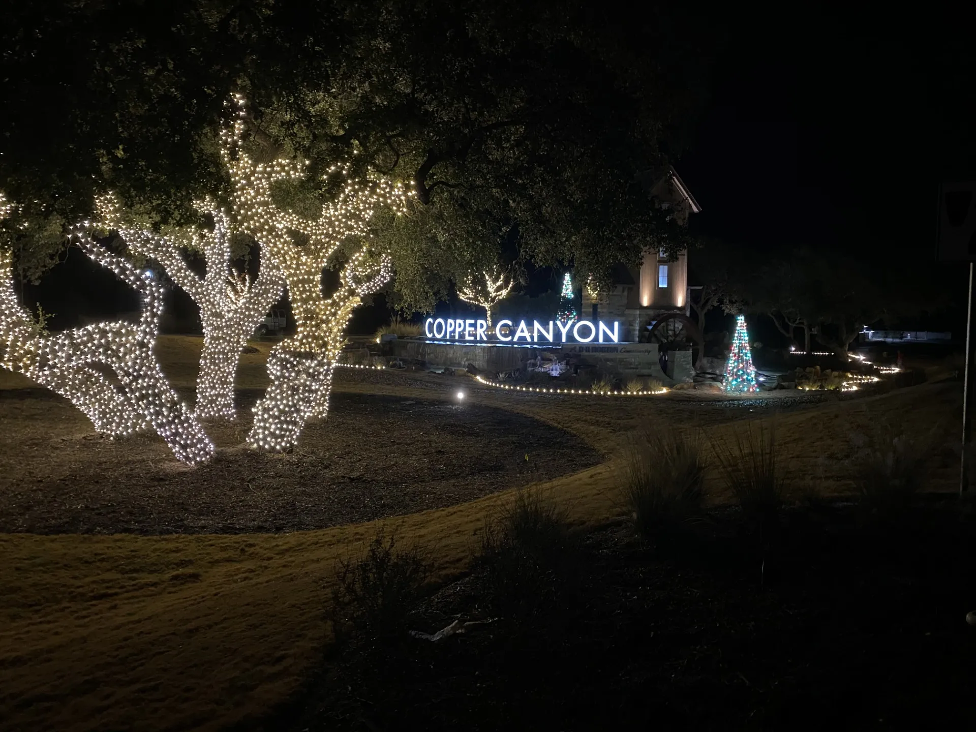 Community entrance with holiday lights and lit garland at night