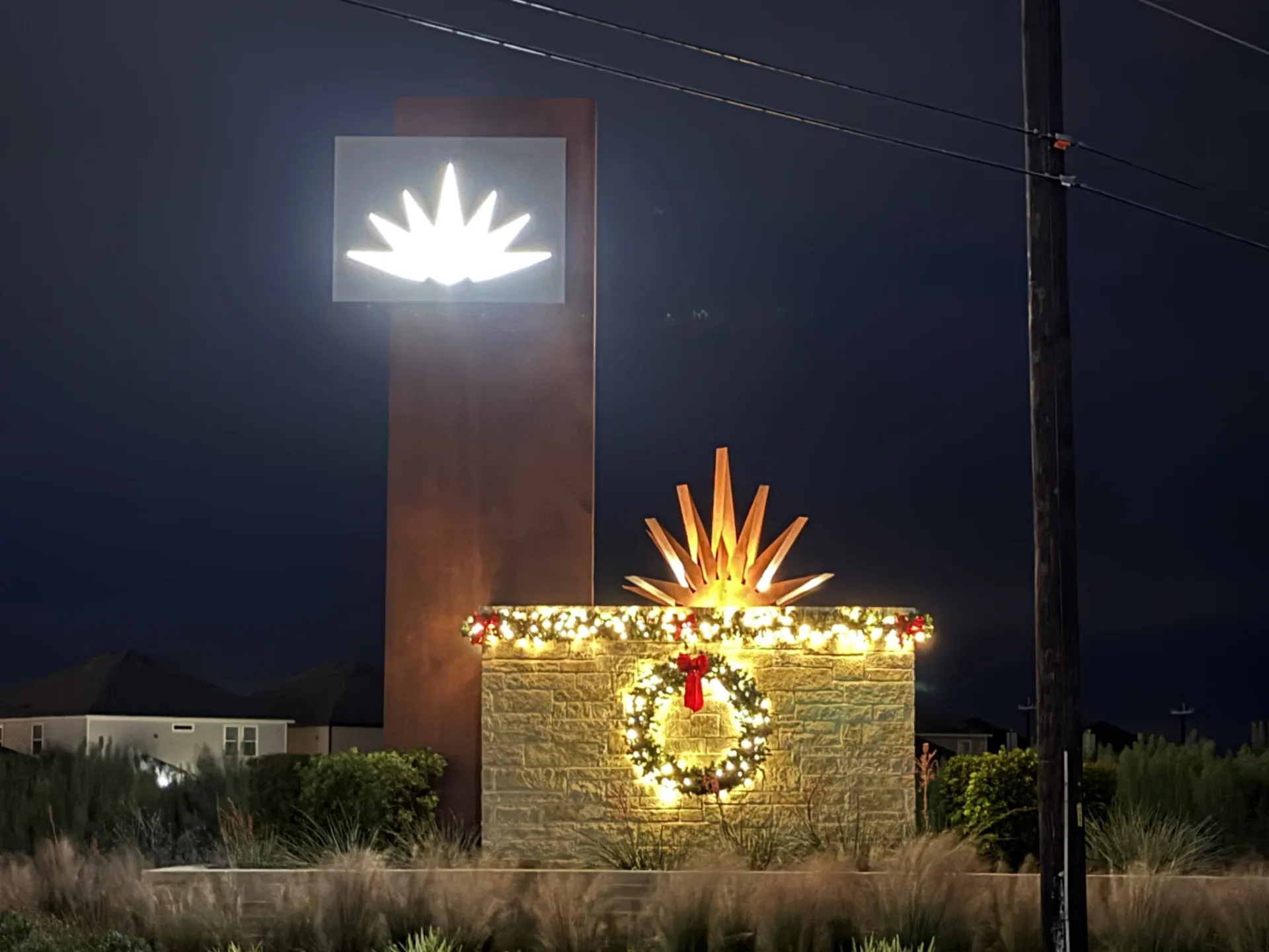 Community monument with lit greenery and a holiday wreath